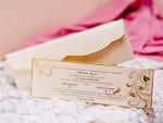 un plic alb cu margini aurii și o invitatie dreptunghiulară