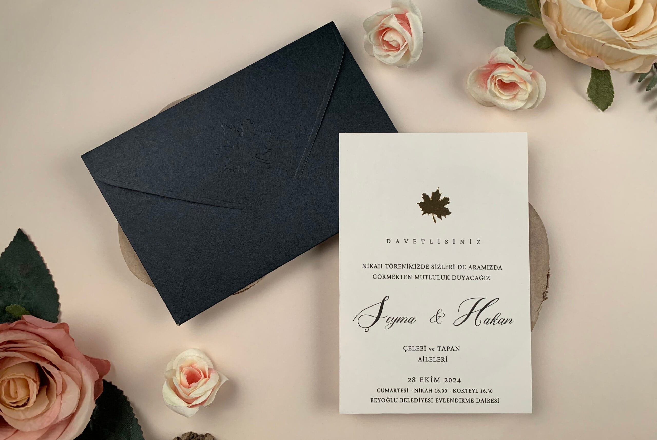 Invitatie nunta eleganta cu plic negru si detaliu auriu un plic negru și o felicitare albă alături de flori roz